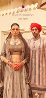 Rewaa Radha-Krishna Collection Women's Designer Embroidered Lehnga Choli with Long Jacket and Dupatta - Earthy Bronze , Rewaa Radha-Krishna Collection Men's Luxury Striped Sherwani with Embroidered Motifs and Red Turban - Sand & Pastel Multi