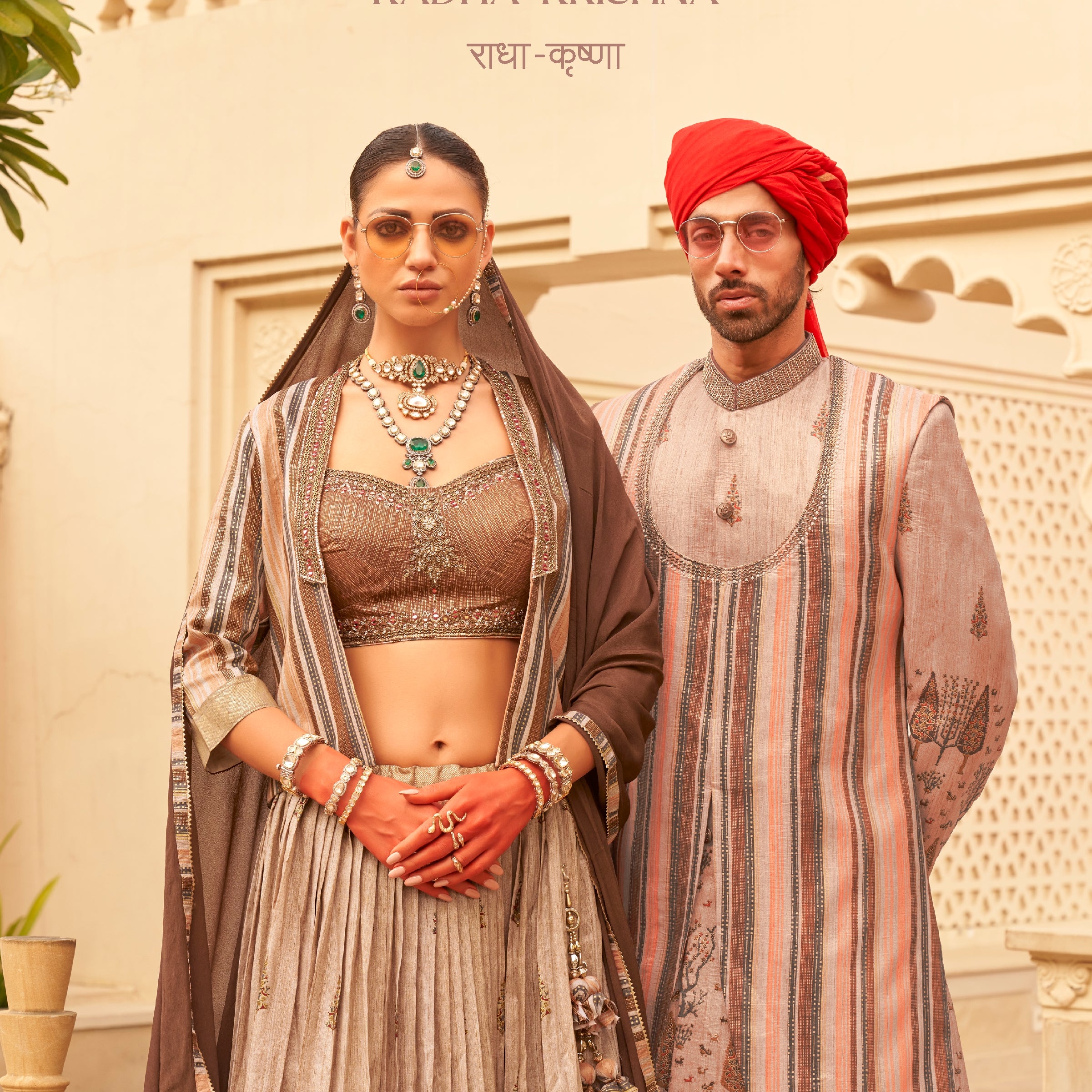 Rewaa Radha-Krishna Collection Women's Designer Embroidered Lehnga Choli with Long Jacket and Dupatta - Earthy Bronze , Rewaa Radha-Krishna Collection Men's Luxury Striped Sherwani with Embroidered Motifs and Red Turban - Sand & Pastel Multi